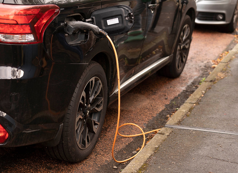 A photograph of an electric car being charged via the cross-pavement charging installation