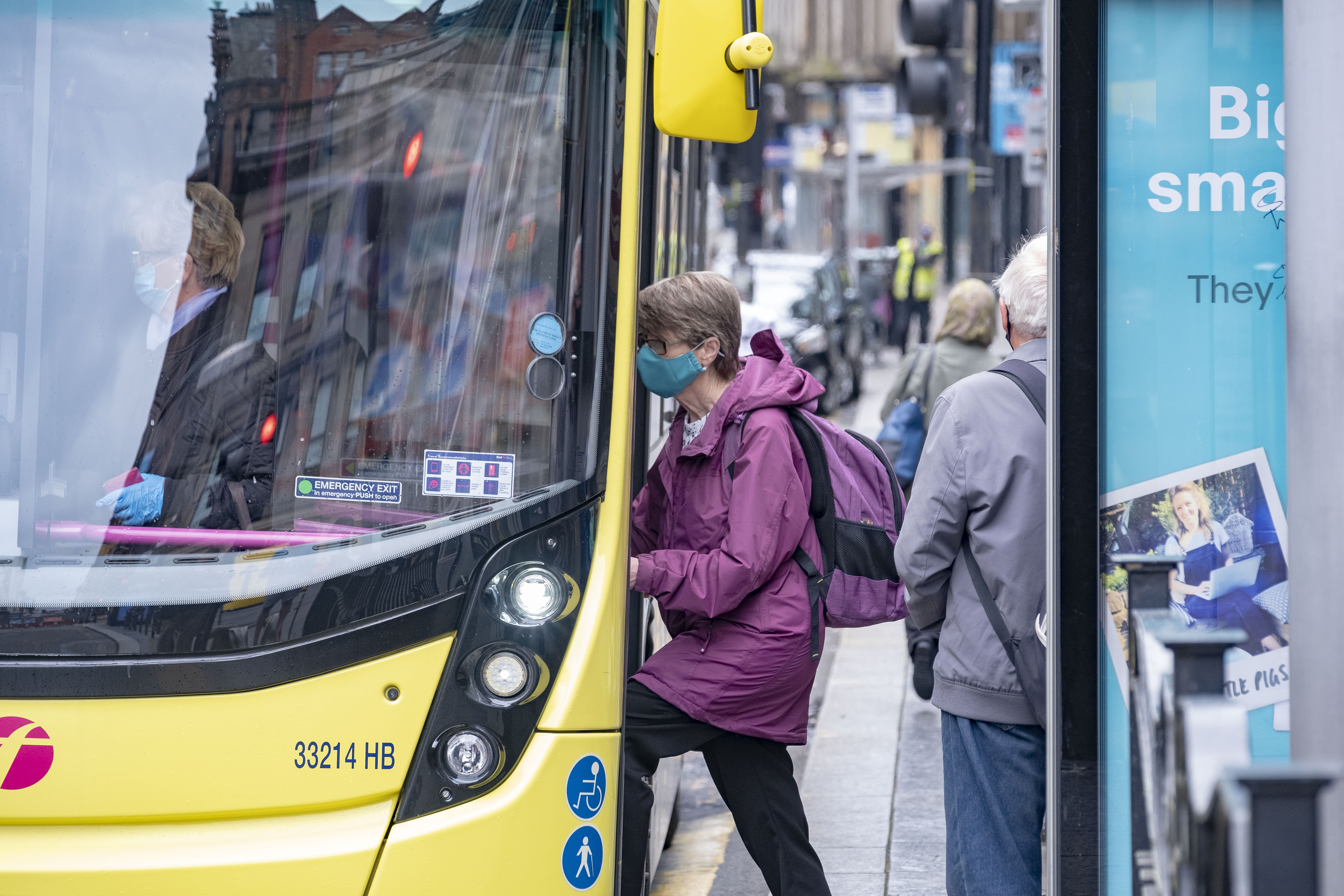 Passenger entering a bus and wearing a face covering