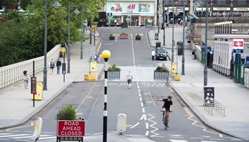 A cyclist uses a stretch of road that has been closed to cars to make extra room for active travel.
