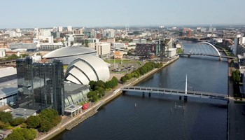 Aerial view of the River Clyde by the SEC complex, with the Glasgow cityscape in the background.