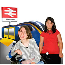 2 young women with a train behind them at a train station.