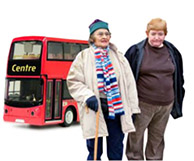 2 older women standing in front of a double decker bus.