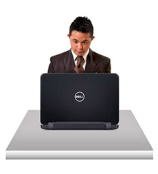 A young man sitting at a desk using a computer.