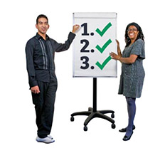  A man and a woman standing presenting next to a flipchart. The chart page shows the numbers 1, 2 and 3 with green ticks next to each number.