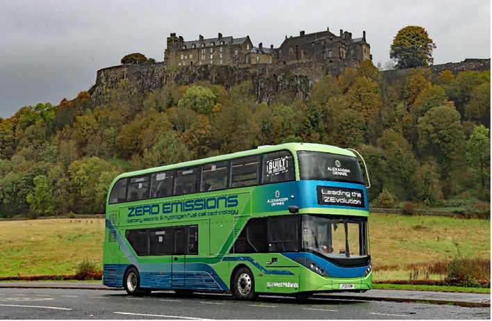 A green and blue zero emissions bus sits on the road with Edinburgh Castle in the background.
