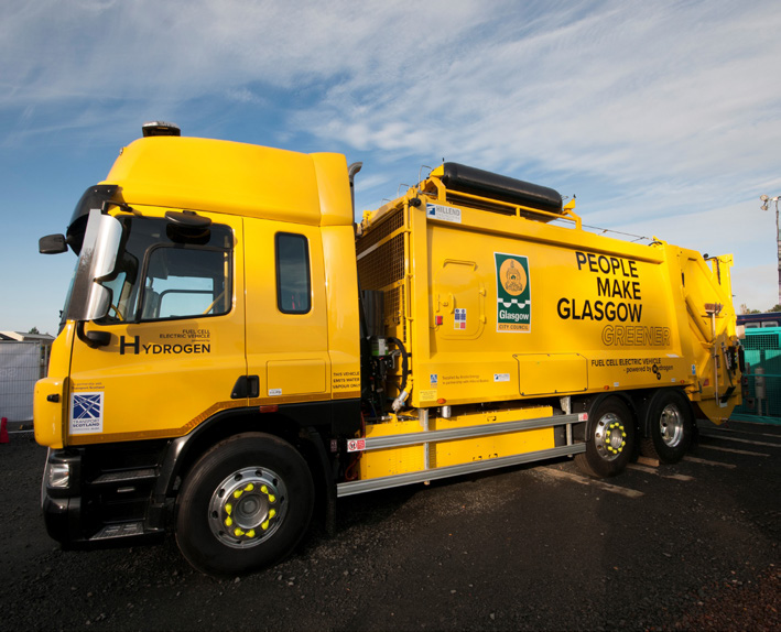 A yellow hydrogen powered bin lorry, with People Make Glasgow written along the side, as well as the Glasgow City Council logo.