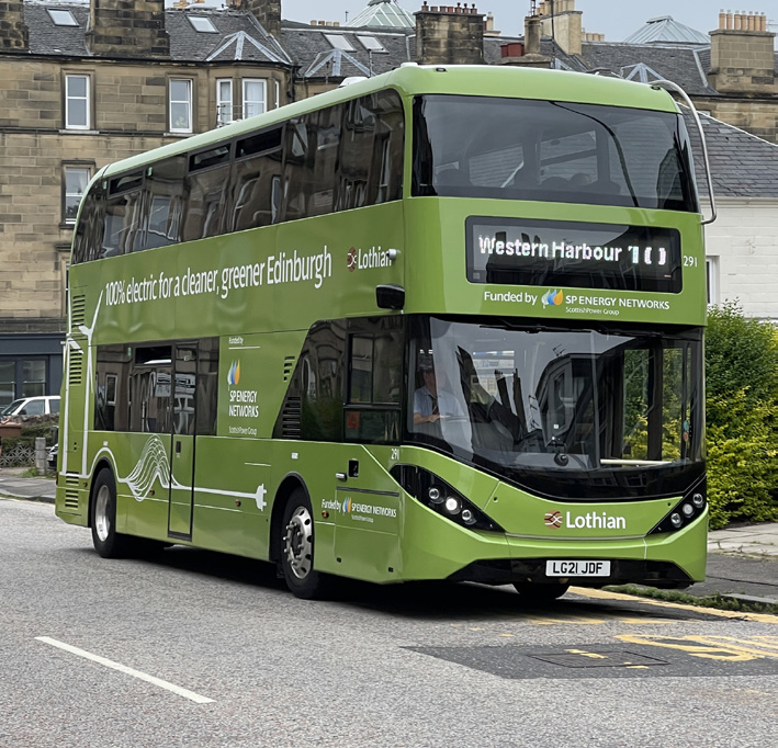 A green number 10 electric double decker Lothian Bus driving through Edinburgh.