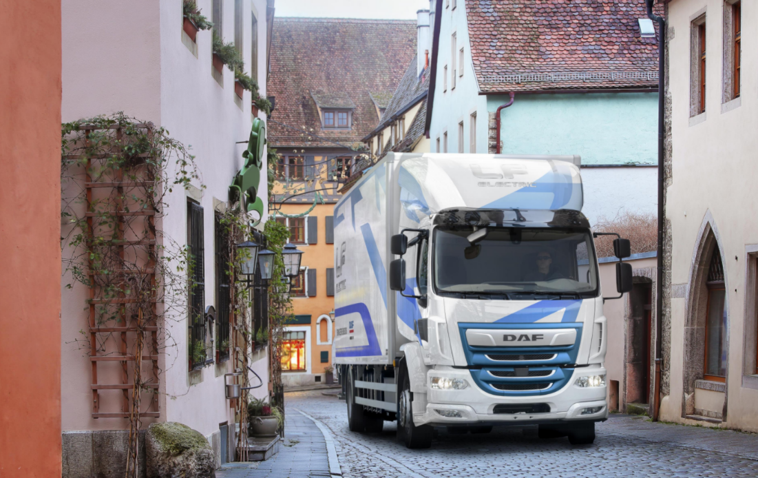 Image shows a Battery Electric Truck driving through an urban setting.