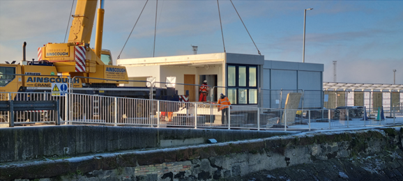 Troon harbour terminal building being lowered by crane