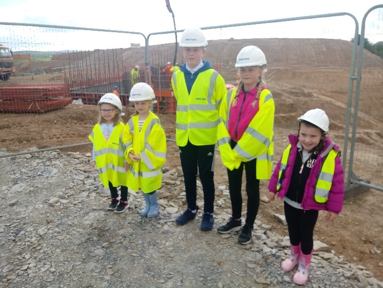 Five children wearing protective jackets and hard hats