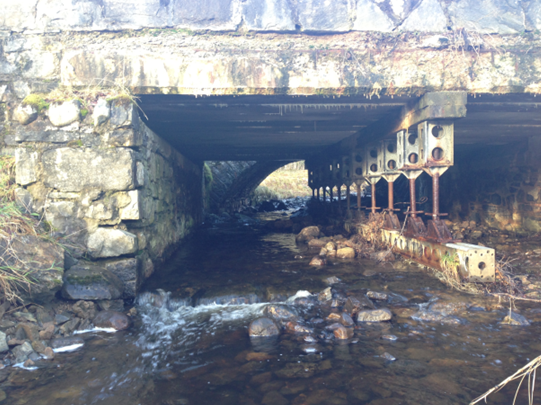 Upstream view of existing Allt Lagain Bhain Bridge crossing running water - shows the temporary props in place since 2001