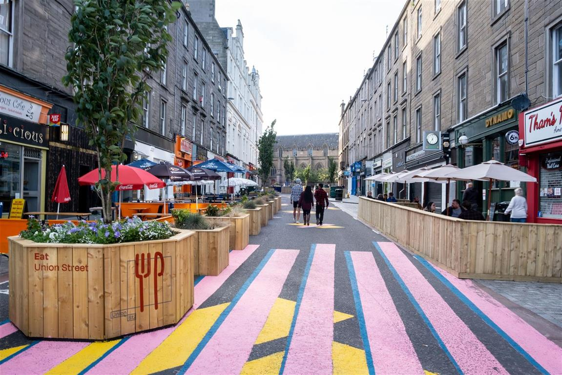 A city street in Dundee, without traffic - instead having seating and outdoor restaurant areas, with pedestrians able to walk in the road in safety