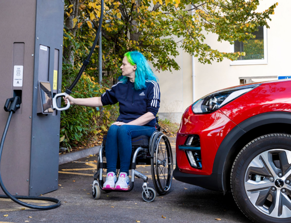 A picture of a person in a wheel chair using an electric vehicle charge point that has been designed for ease of use.
