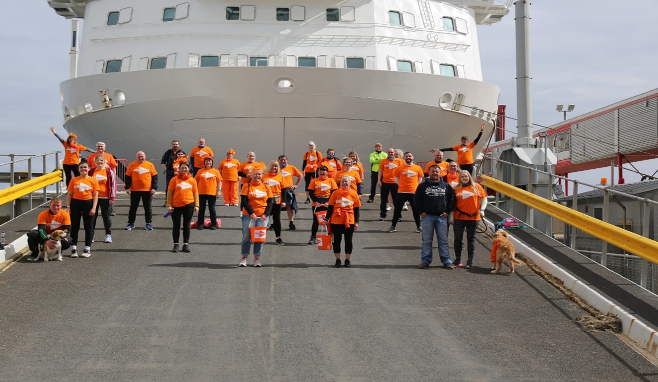 Photograph of a large group of Serco Northlink Ferries crew members standing infront of a ferry with branded charity tshirts and collection buckets before sponsored walk