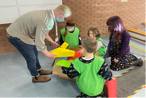 Photograph of three school pupils with teacher and Jacobs employee with colourful plastic building blocks for building activity