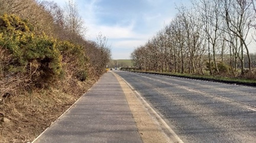 The newly constructed pavement running alongside the road.