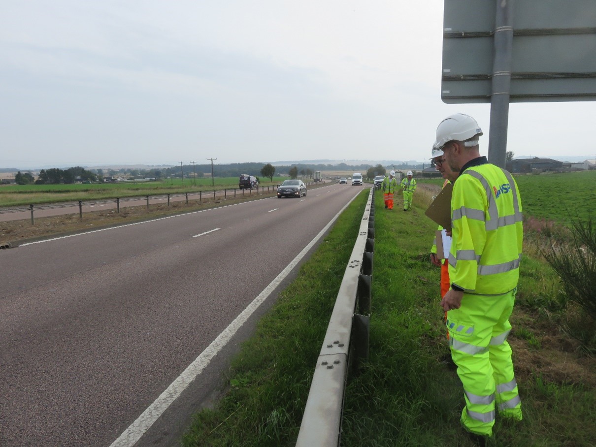 A person in bright safety gear inspecting a road surface