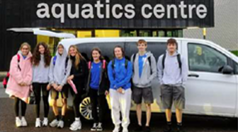 Members of the Falkirk Swim Team standing in front of a car