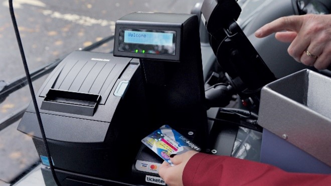 A photograph of a person using a concessionary card on a bus