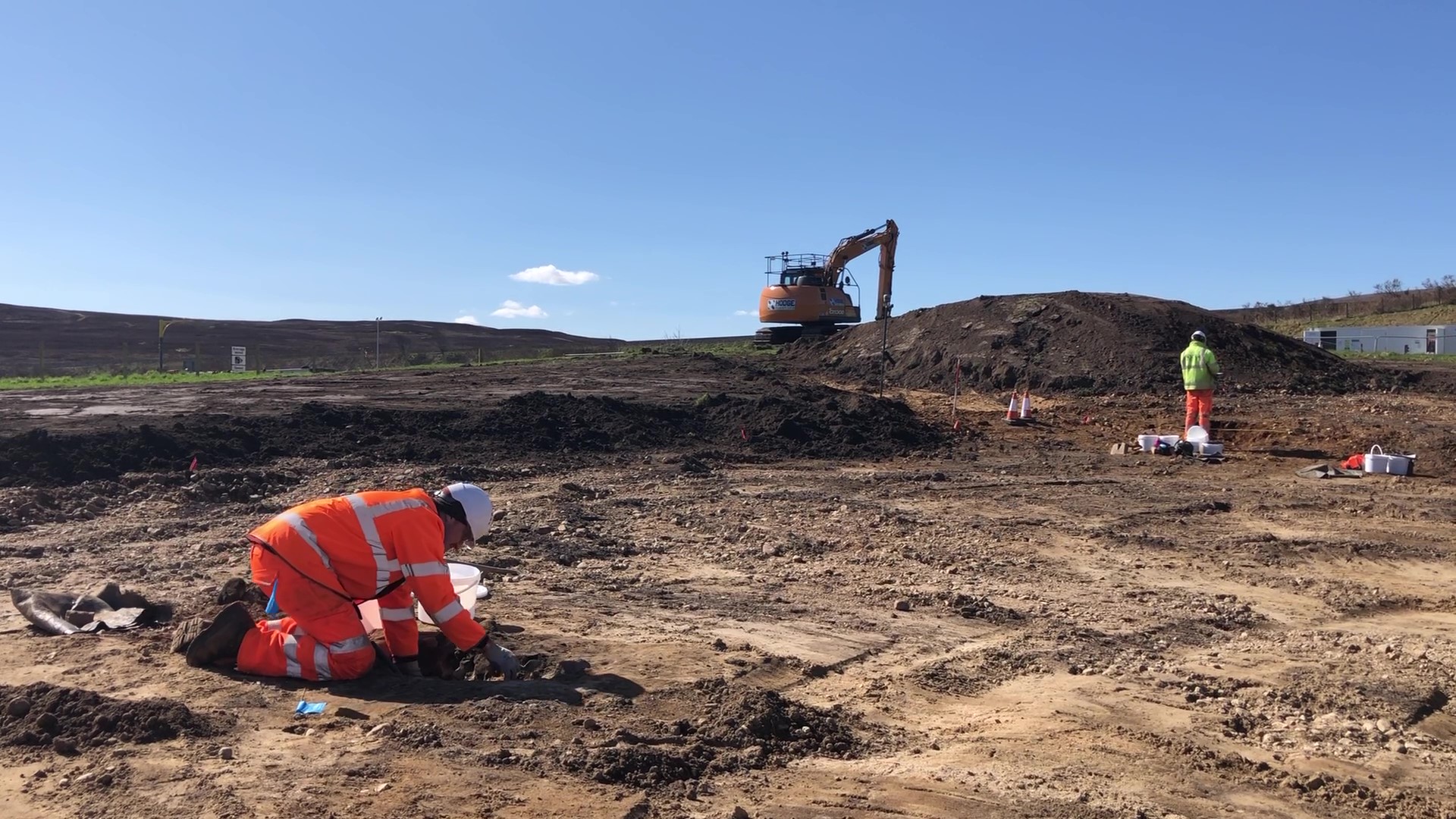Workers doing ground investigations. A digger is visible in the background.
