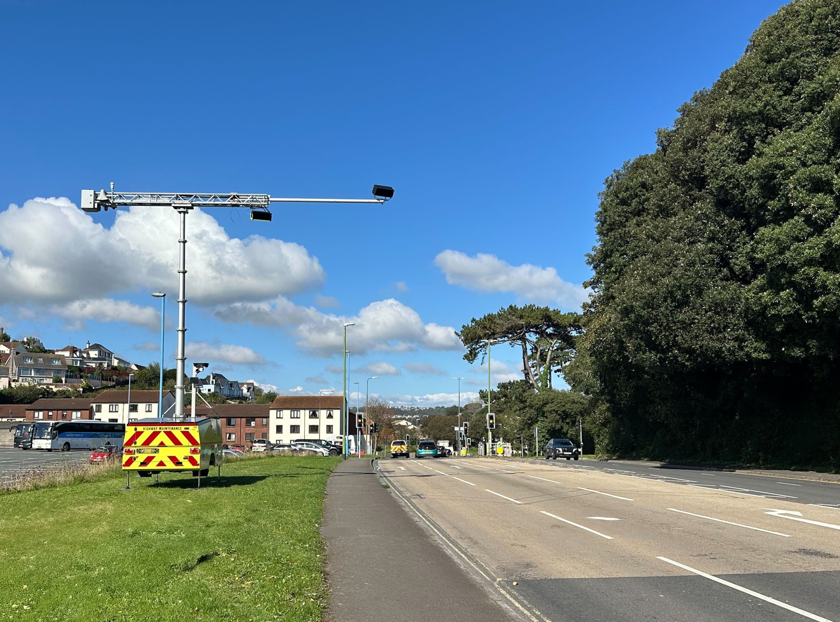 A trailer with cameras that can detect distracted drivers using phones or not wearing seatbelts, beside a road